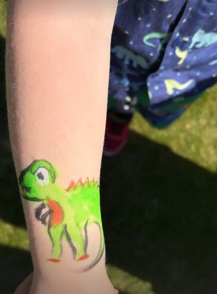 A child's arm with a drawing of a dinosaur