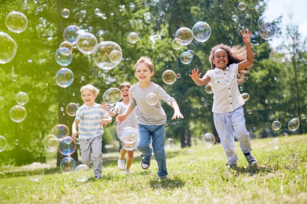Friends enjoying warm sunny day with soap bubbles