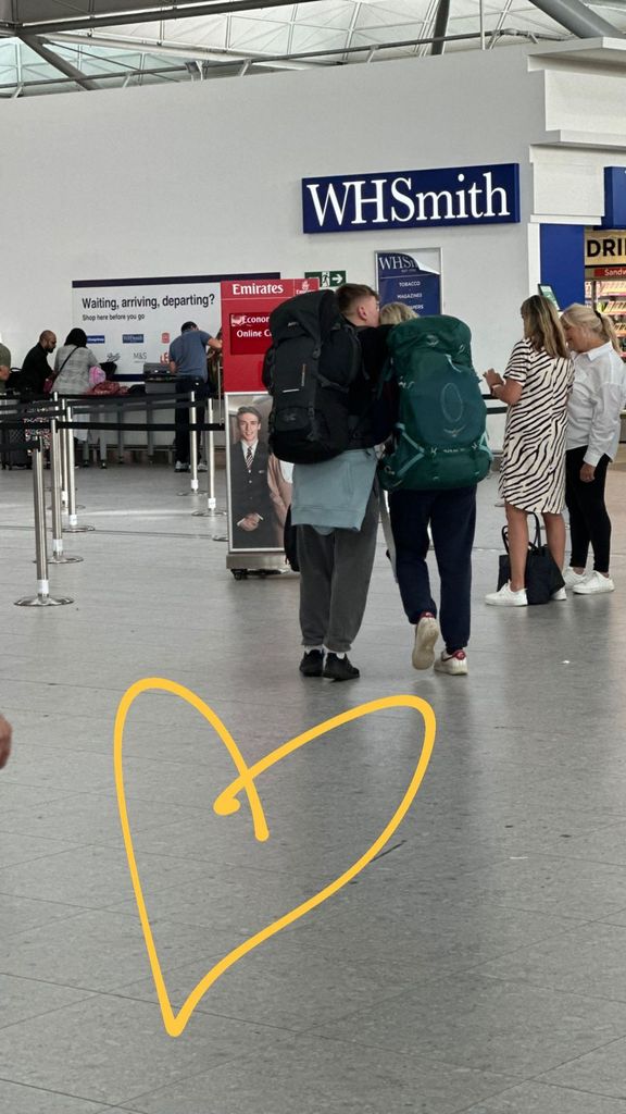 Two people hugging at the airport as they make their way to security