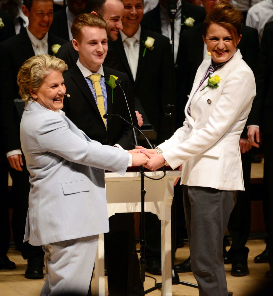 Sandi Toksvig in a blue suit holding hands with wife Debbie 