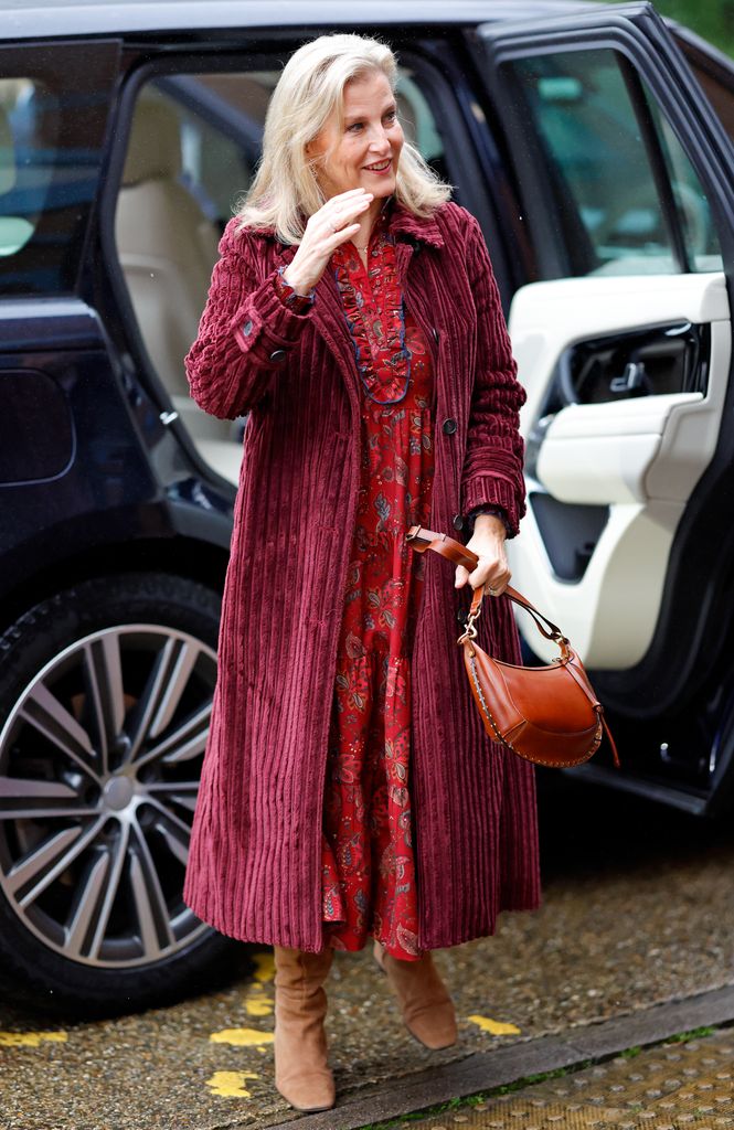 Sophie  exiting car in red patterned dress and tan boots