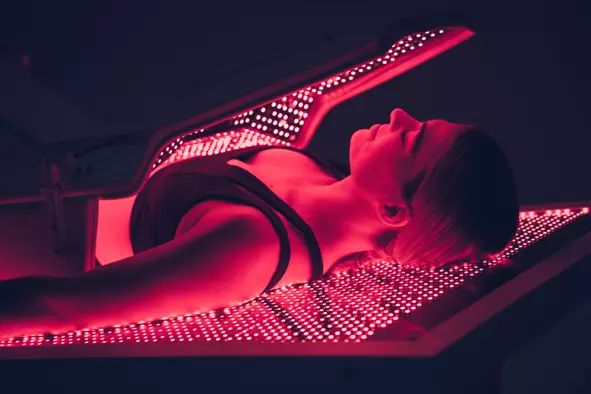 Woman lies inside Red Light Therapy machine