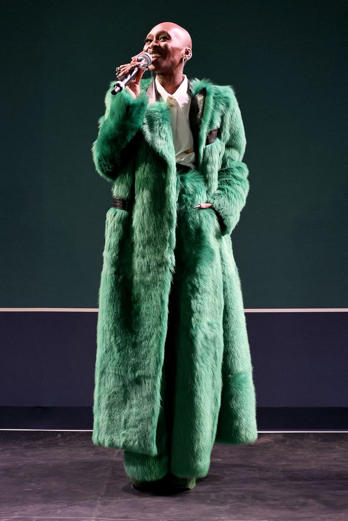 Cynthia Erivo on stage in fur green coat and pants