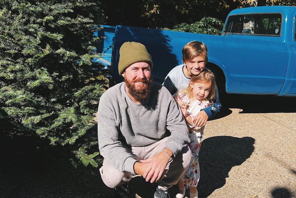 Danny with Rani and Bingham in a garden next to a blue truck
