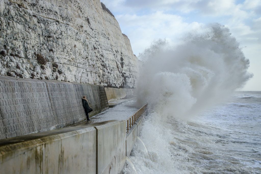 A woman watching waves crash over a cliff