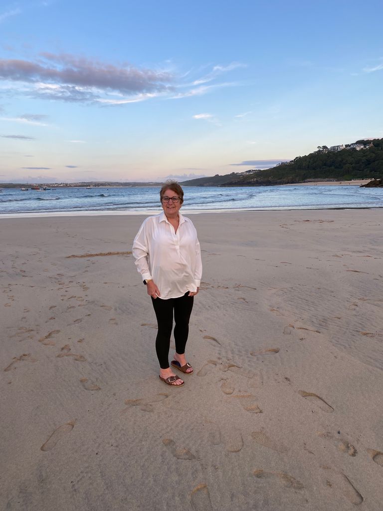 woman standing on the beach in a white shirt