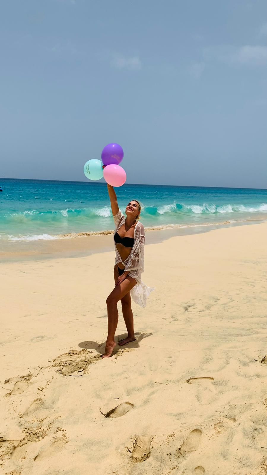 Woman holding balloons on the beach