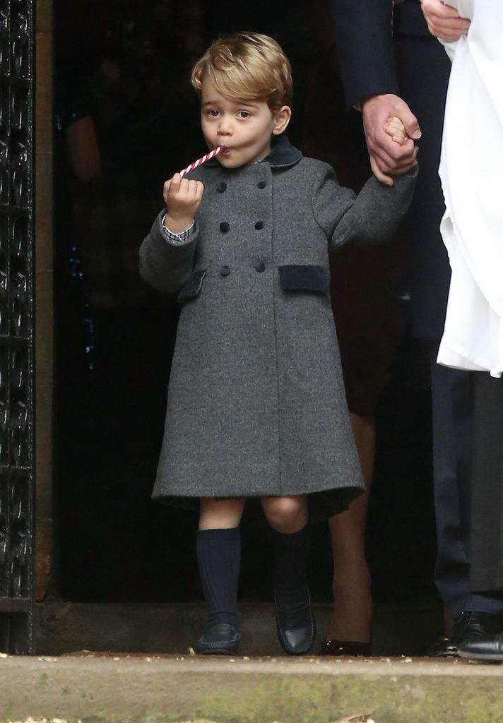 Prince George licking a candy cane in a grey coat