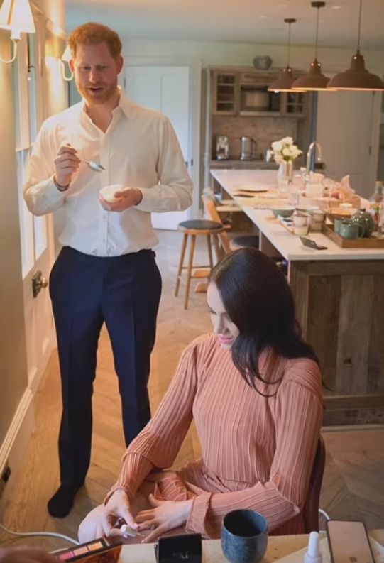 Prince Harry eating a yoghurt and Meghan Markle painting her nails in the kitchen