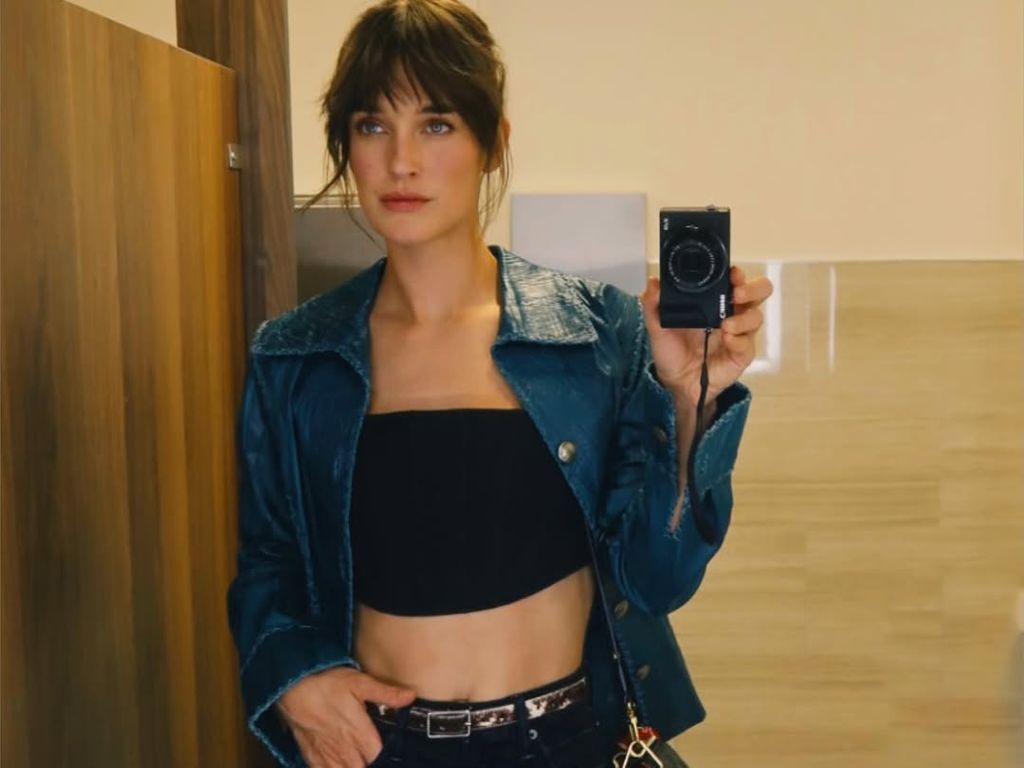 Kate posing in mirror in blue leather jacket and black crop top