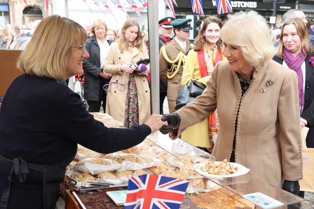 A Rainha Camilla aperta a mão de um comerciante durante sua visita ao Farmers' Market em 27 de março de 2024 em Shrewsbury, Inglaterra. 