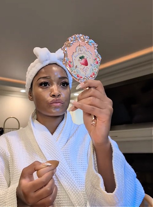 Keke Palmer holding mirror while wearing a bathrobe