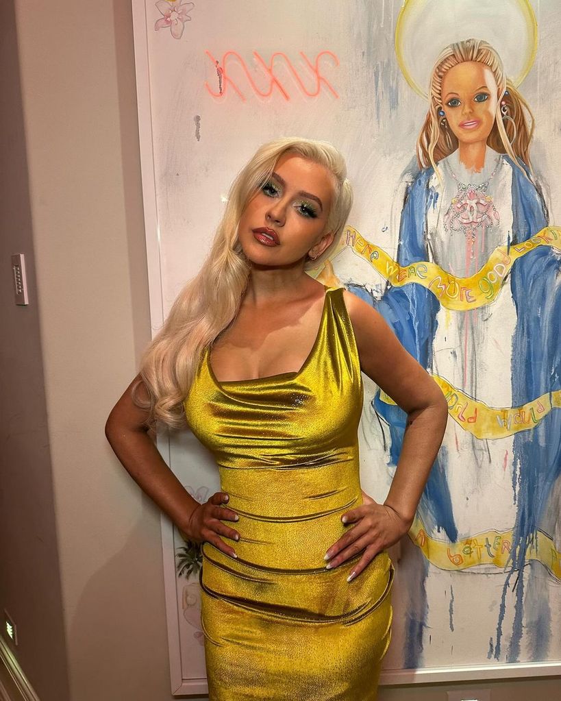 Christina Aguilera posing in yellow dress in front of artwork