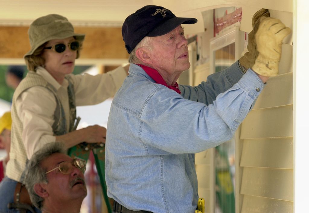 Jimmy Carter and his wife Rosalyn attach siding to the front of a Habitat for Humanity home being built June 10, 2003 