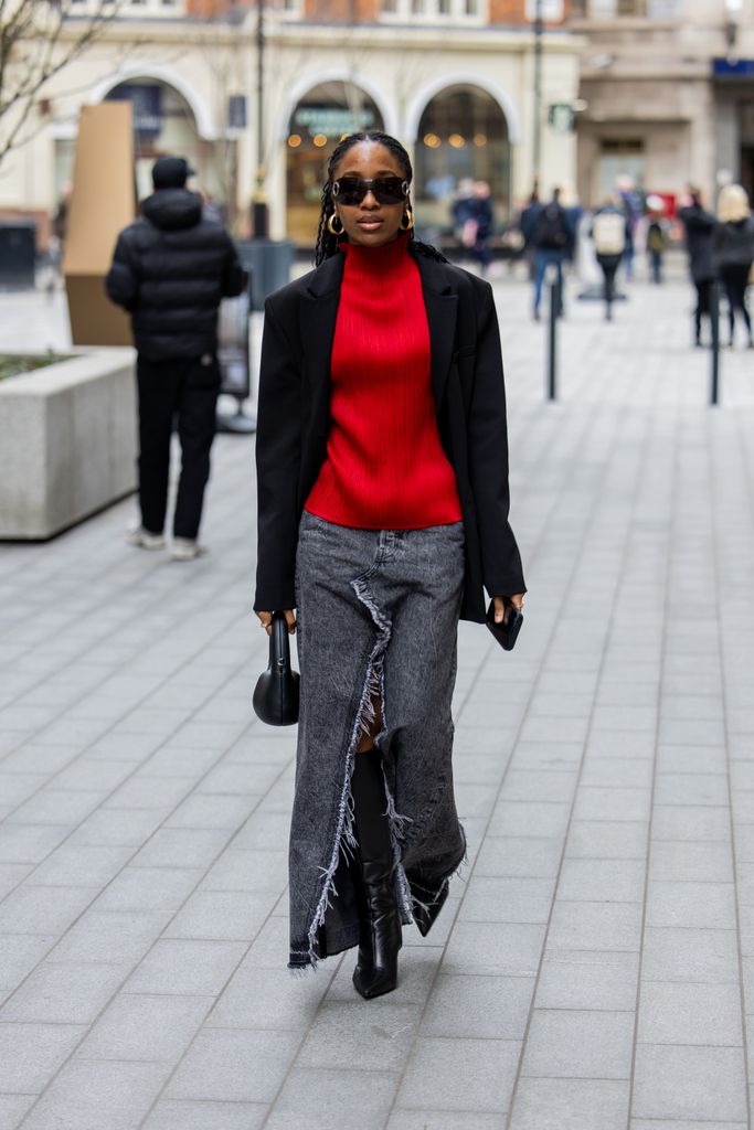 A guest  wears red turtleneck, black blazer, grey denim jeans skirt with slit outside Mark Fast during London Fashion Week February 2024 on February 16, 2024 in London, England. (Photo by Christian Vierig/Getty Images)