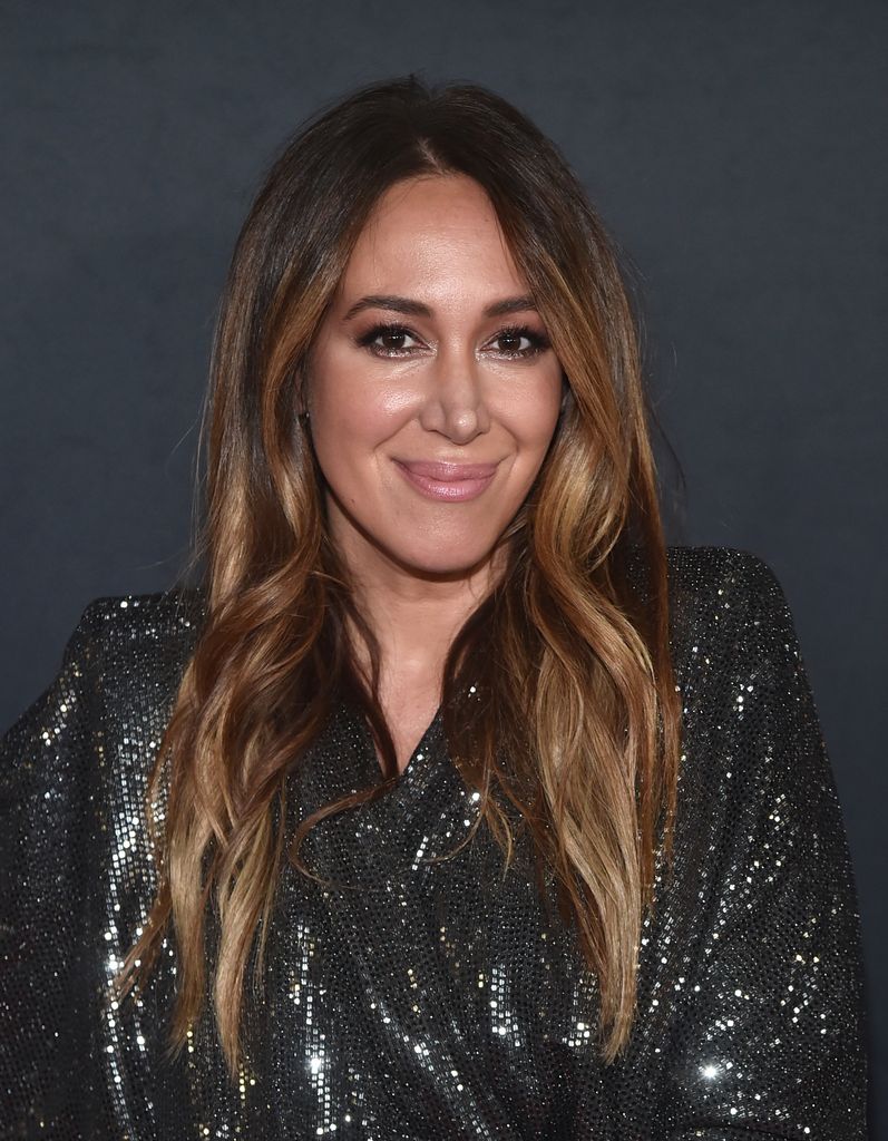 Haylie Duff porte une robe noire scintillante et sourit à la caméra.