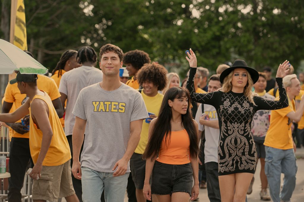 man and two women walking through busy crowd of students