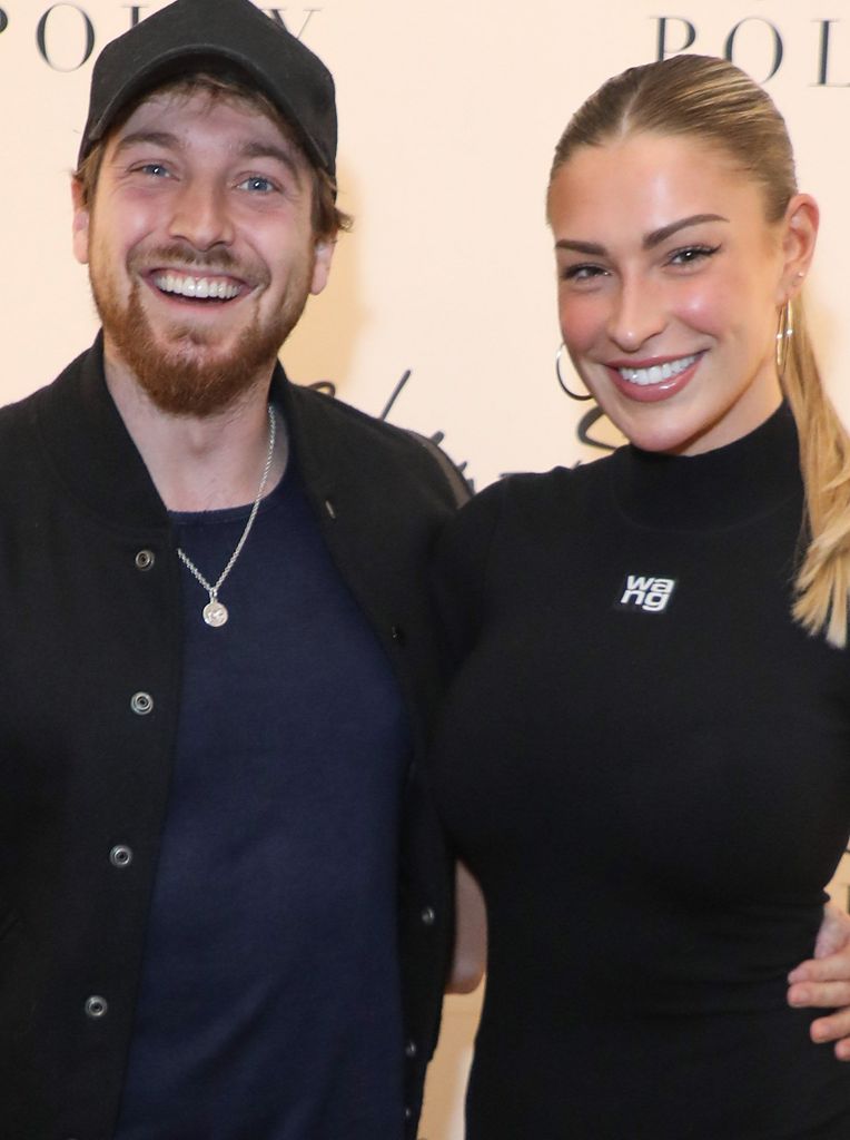 Sam Thompson e Zara McDermott sorriem enquanto posam em frente à marca para evento de moda