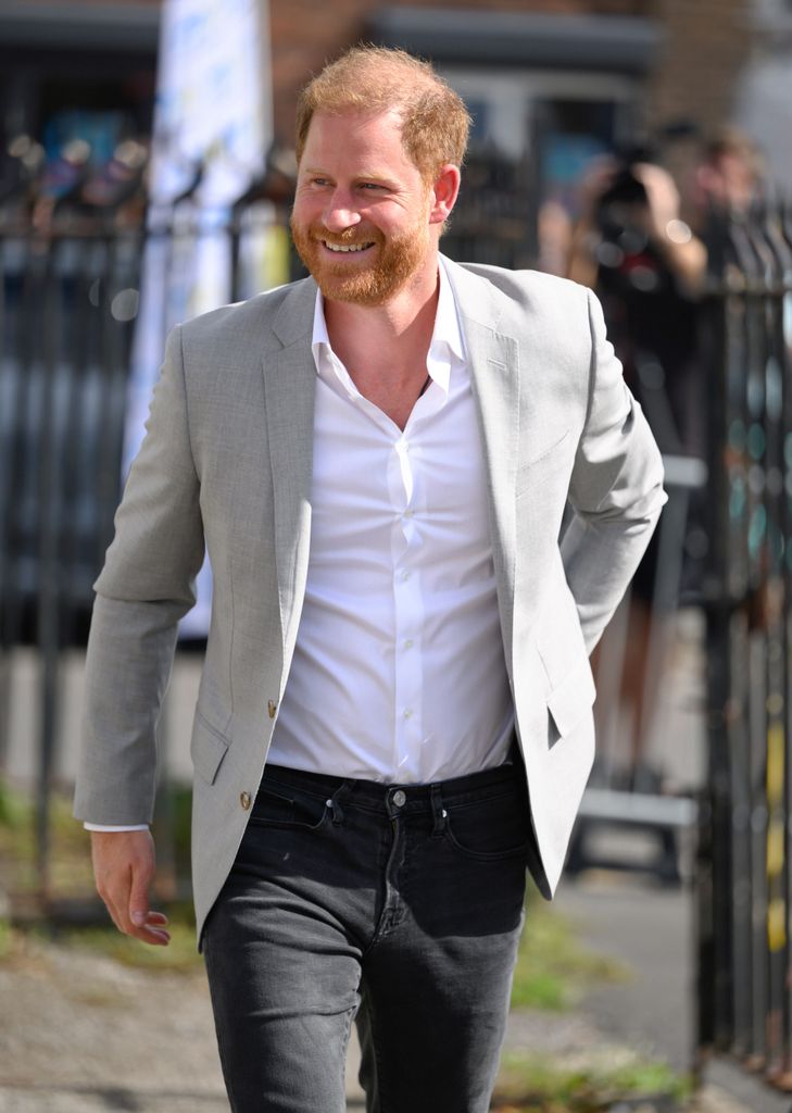 Prince Harry smiling in white shirt and grey blazer