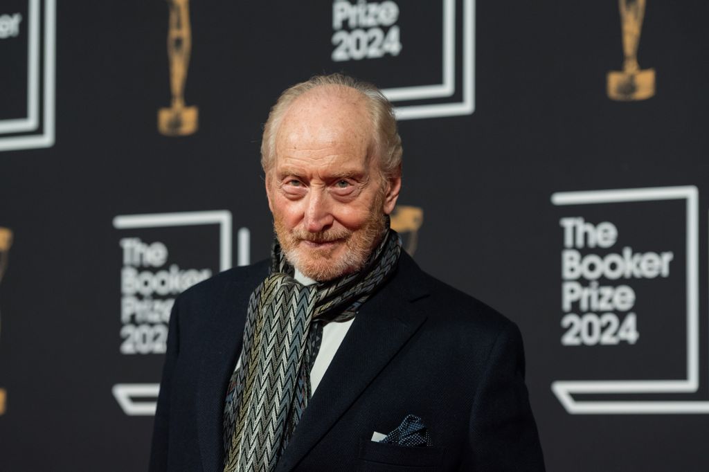 Charles Dance in a suit, wearing a warm scarf