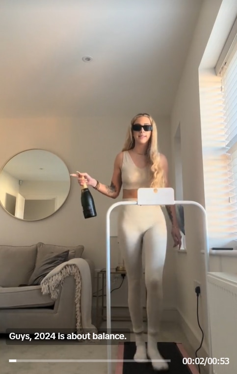 GK barry on treadmill in her living room holding bottle of wine