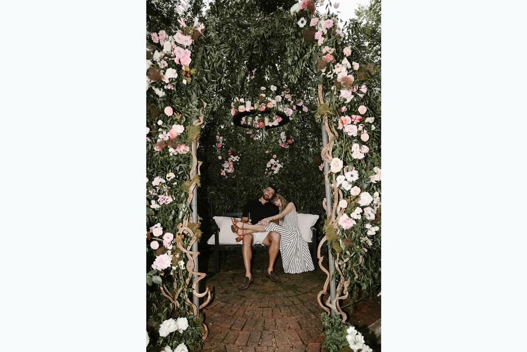 Taylor Swift sits with her legs on Travis Kelce's lap inside a gazebo