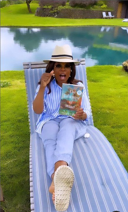 oprah winfrey holding book lounging by pool at home