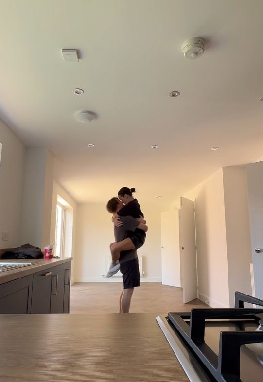 Ben Joyce lifting Amber Davies up and kissing her, a kitchen can be seen in the foreground