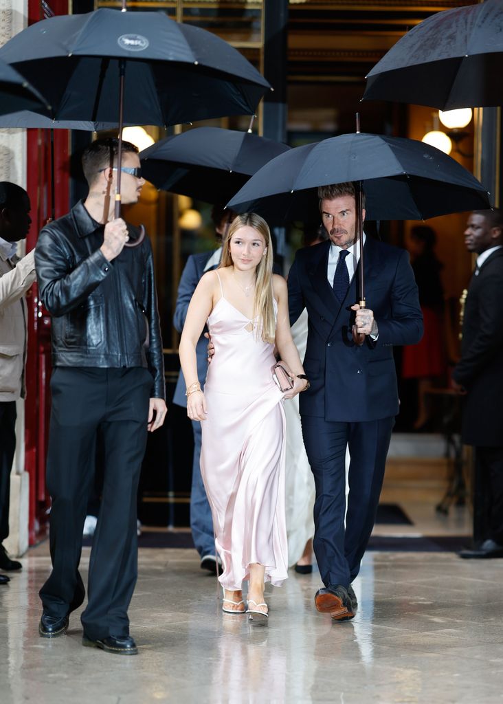 Harper usou um vestido blush na chuva, caminhando com David e Brooklyn Beckham sob guarda-chuvas. Seu vestido delicado e esvoaçante contrastava alegremente com o clima, mostrando sua confiança elegante.