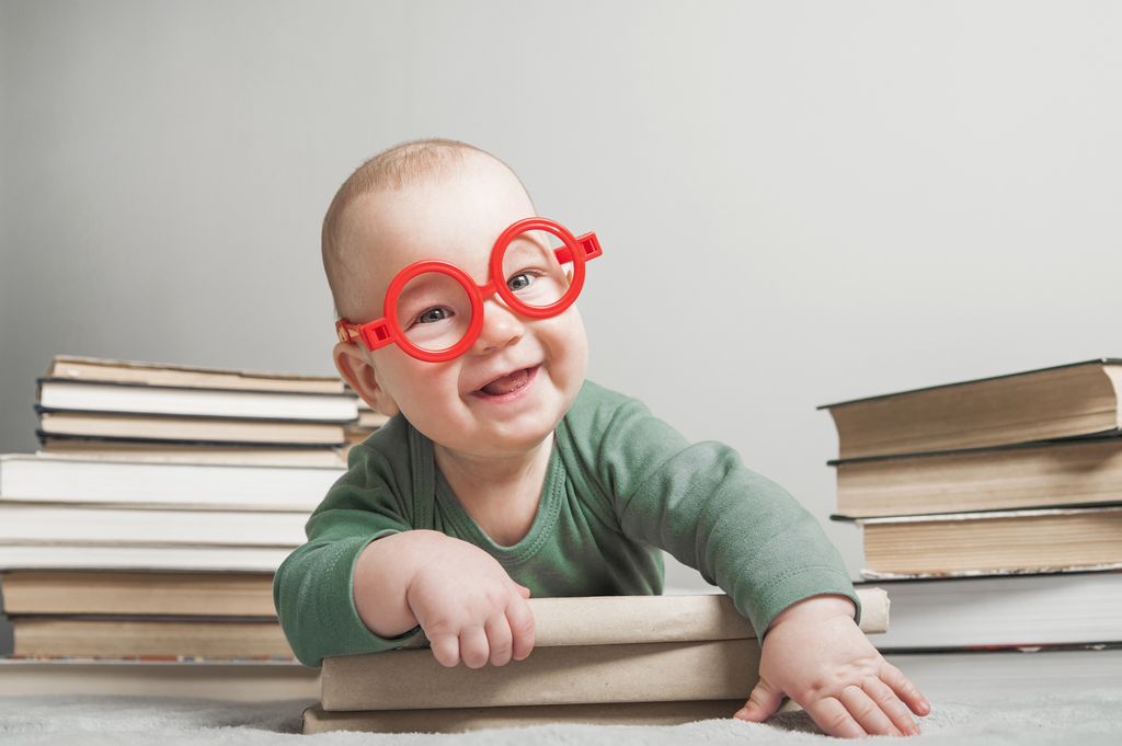 Newborn baby 5 months old with glasses and book close-up and copy space.