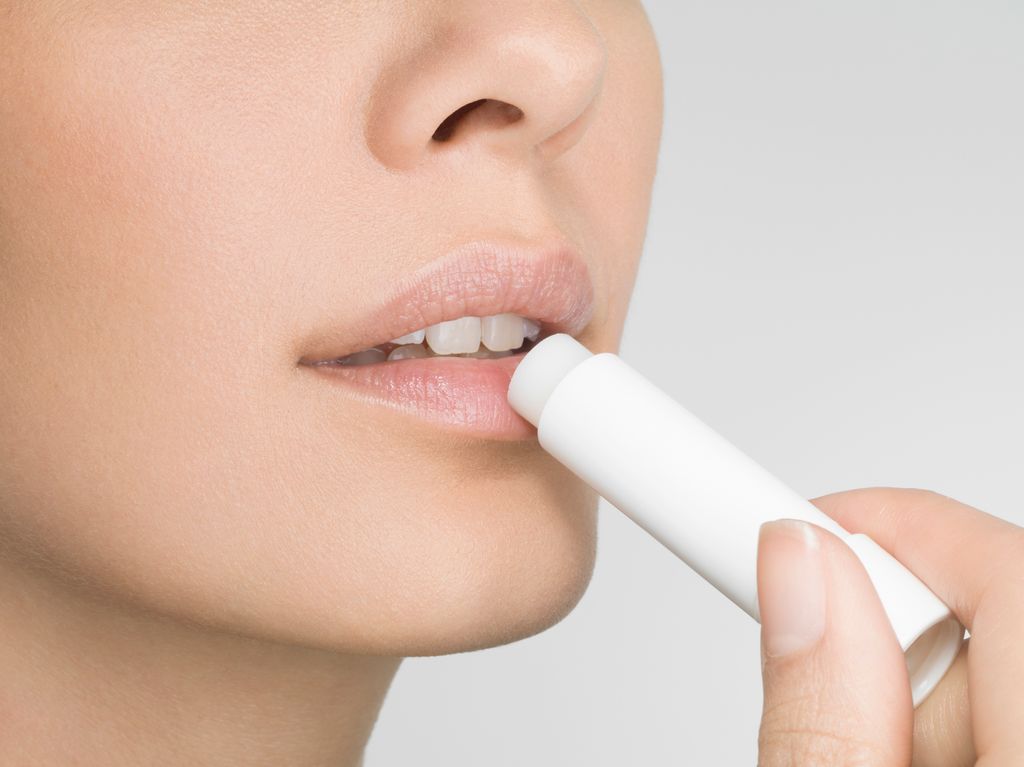 Female applying lip balm, close up, side view