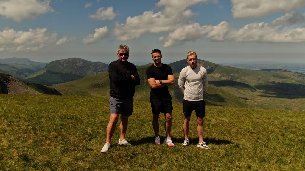 Mark Wright stands in a field alongside his brother and dad