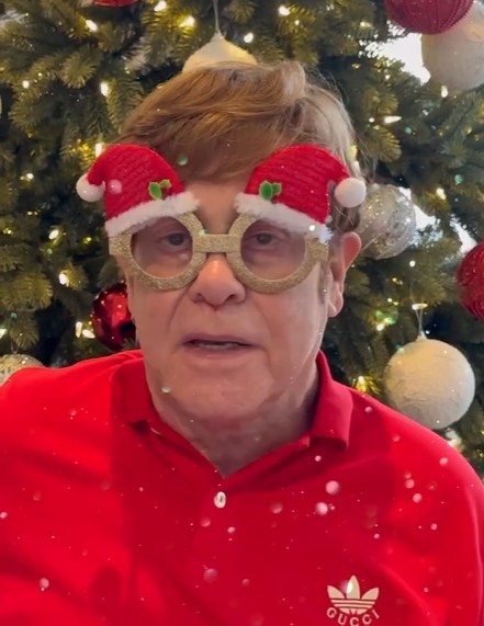 Elton John stepping into Christmas with Santa hat glasses