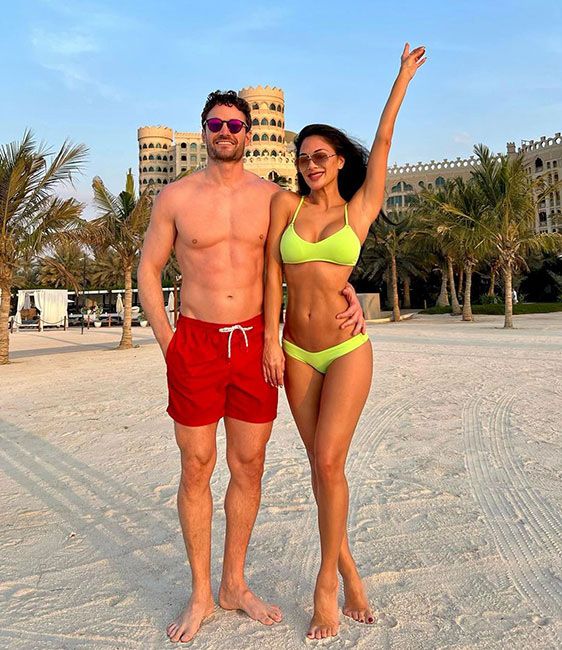 nicole wears a neon green bikini and stands with a man