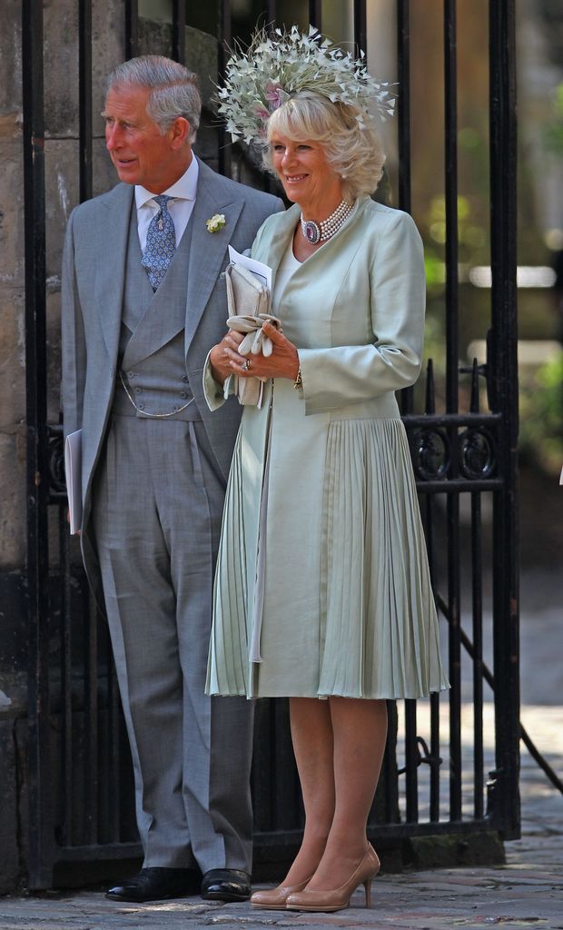 King Charles in a grey suit and Camilla in a green coat dress