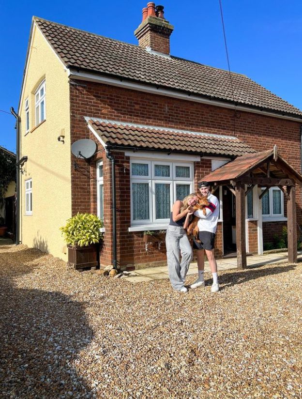 Tasha Ghouri and Andrew Le Page holding a dog while standing outside a house