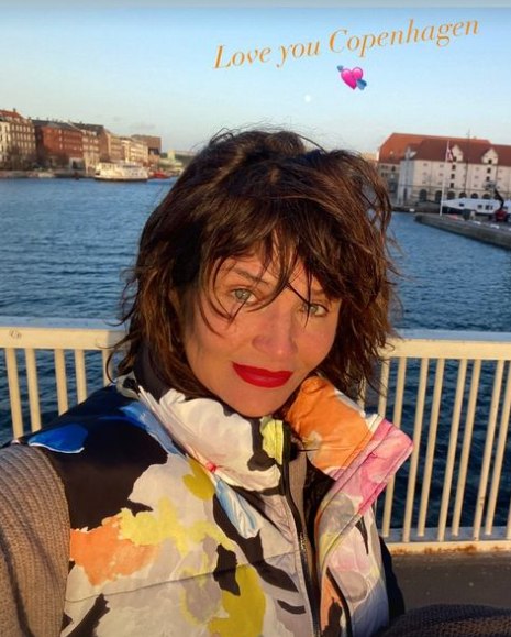 Helena Christensen in colourful jacket posing on Copenhagen bridge 