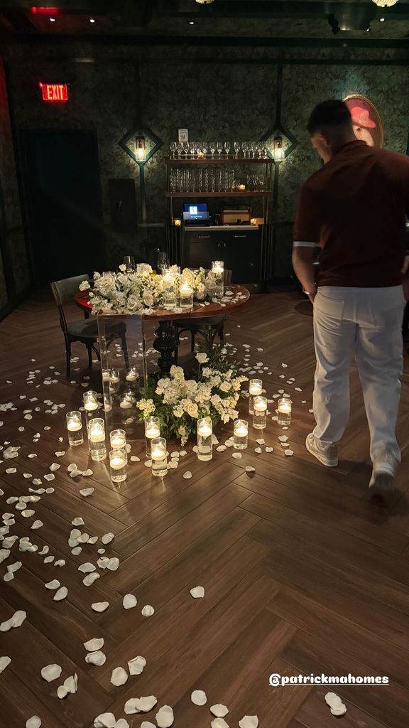 patrick mahomes walking to table covered in flowers candles and rose petals on the floor