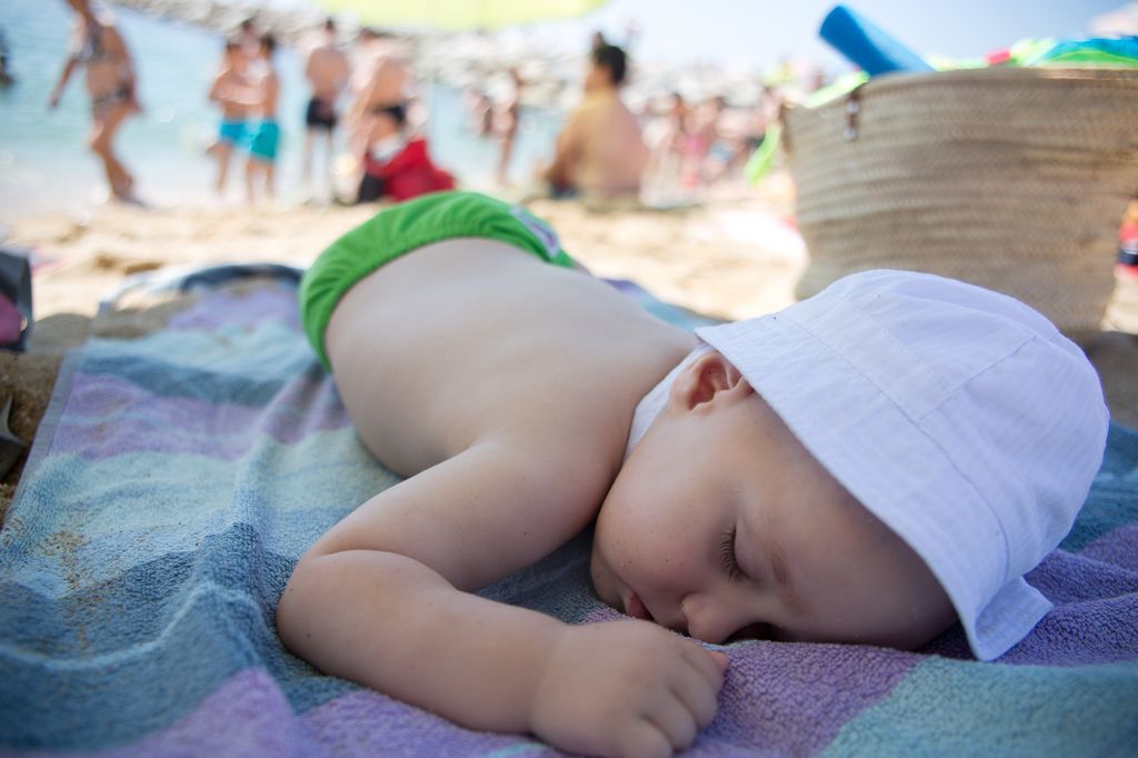 Un petit garçon fait la sieste sur une plage