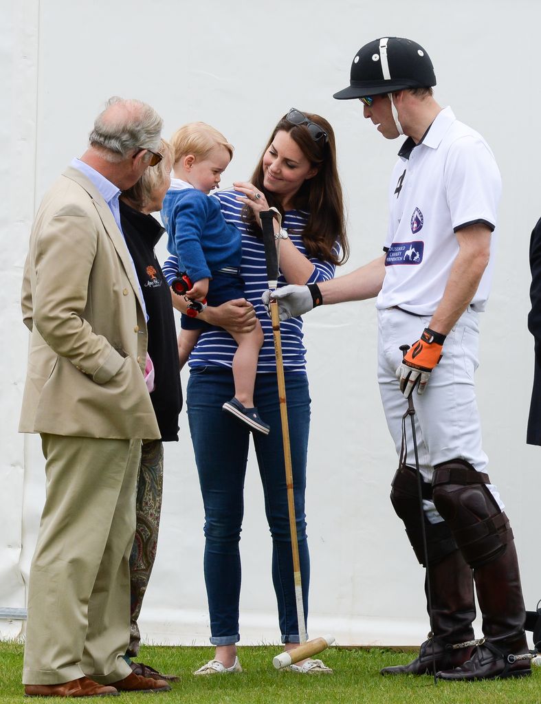 King Charles watches baby Prince George as he is carried by Princess Kate, with Queen Camilla and Prince William standing on either side