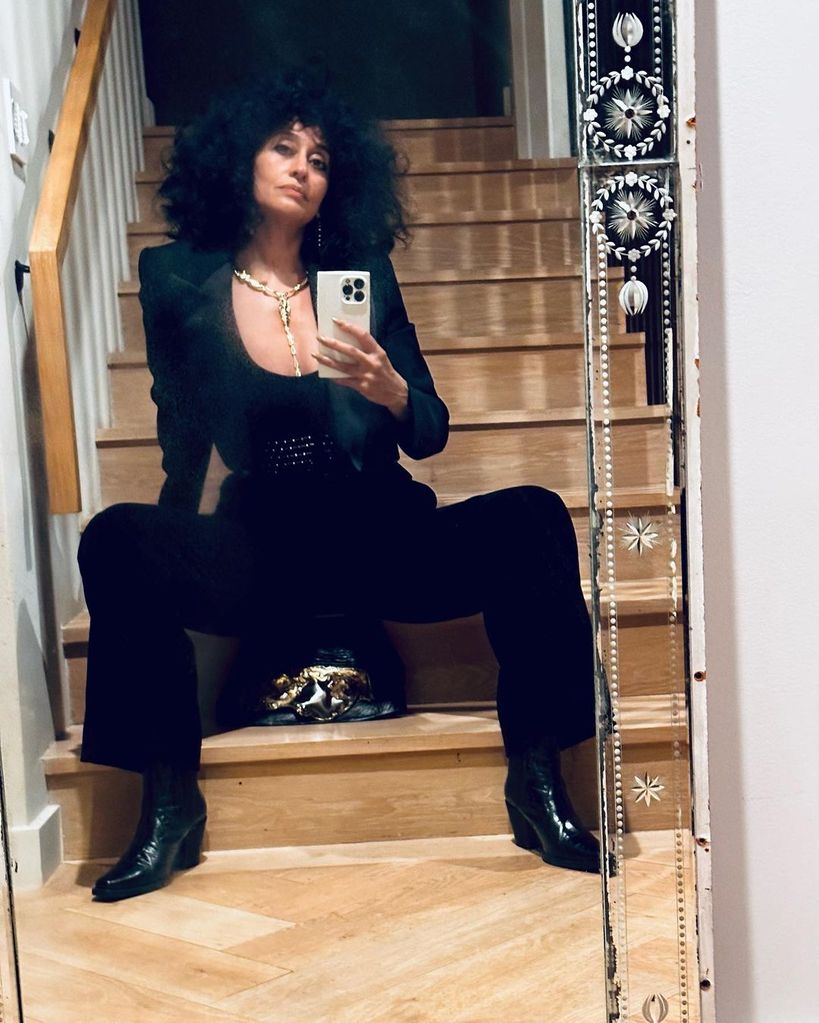 Tracee Ellis Ross wears a black suit and sits on the stairs of her apartment