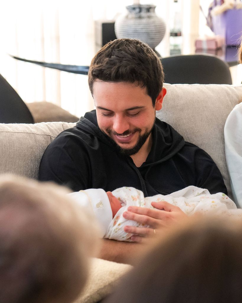 Crown Prince Hussein cradling a baby