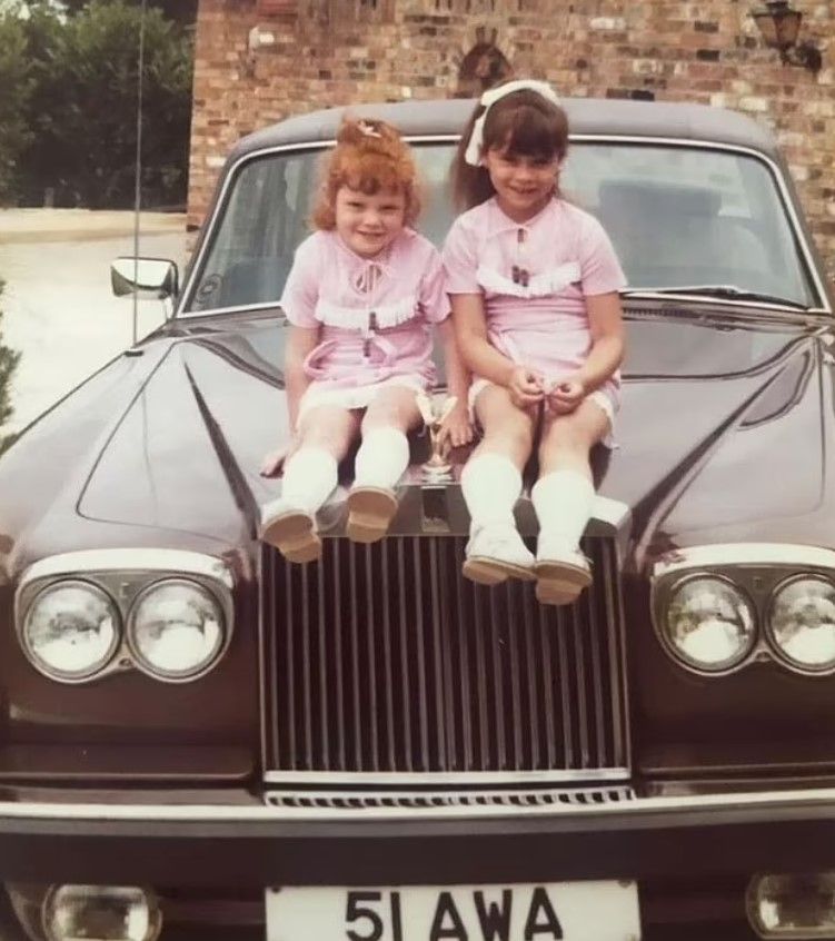 Victoria Beckham posing on Rolls Royce with sister Louise Adams