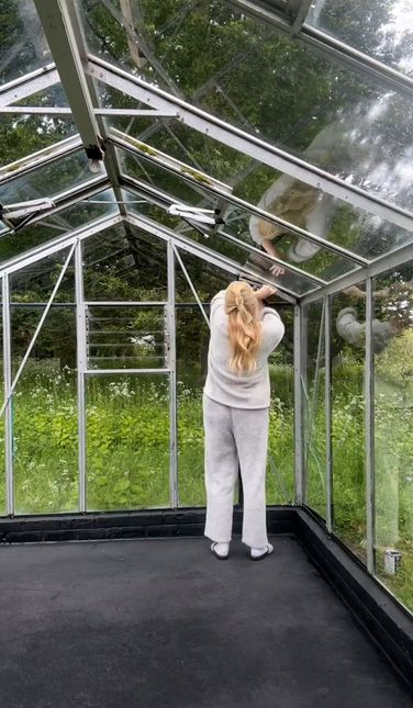 Stacey Solomon in tracksuit painting her greenhouse black
