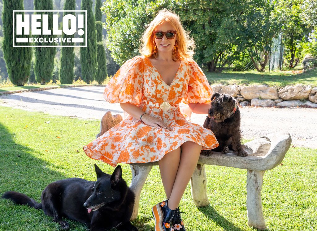 Suzanne Syz posing in Tuscany home in orange mini dress with two dogs