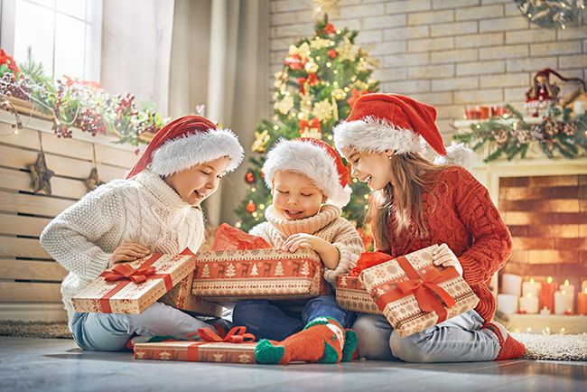 Children opening Christmas presents together smiling