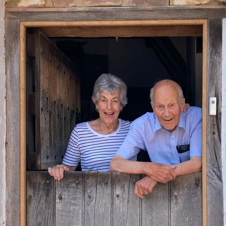 Richard and Anne Spencer smiling from inside a barn door