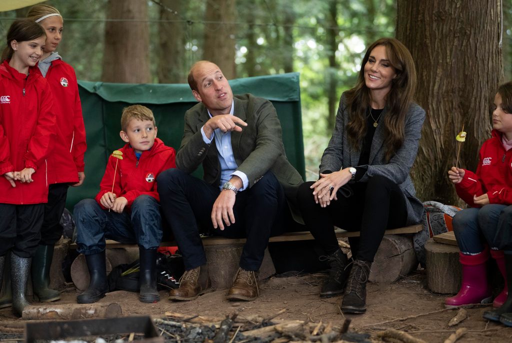 Prince William, Princess Kate and four schoolchildren sat around a wooden area