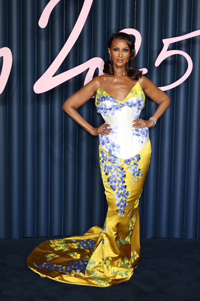 Iman posed in yellow, blue and white floral corset dress