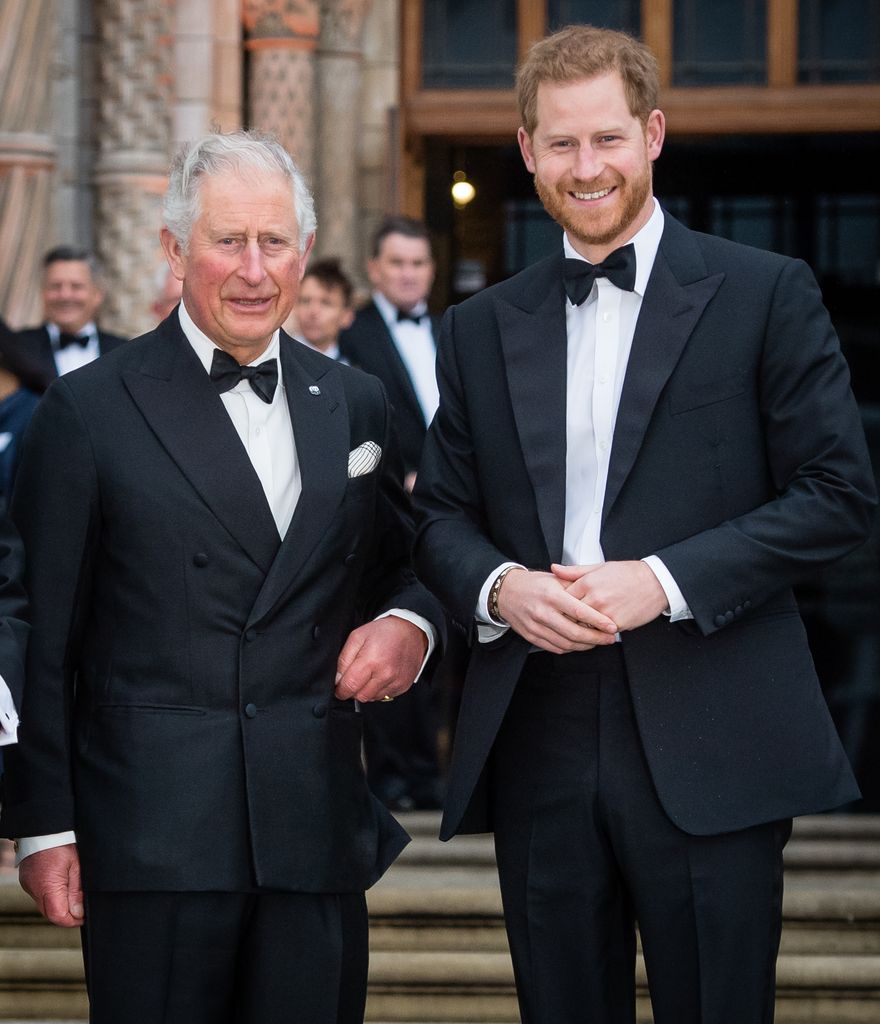 King Charles and Prince Harry smiling in suits